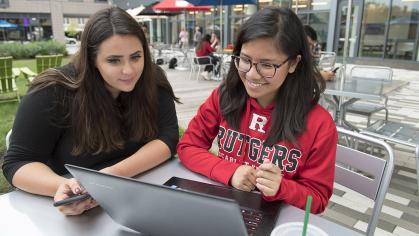 Natalie Stanzione (EMSOP ’21), and Sarah Elechicon (SAS ’19) work on a laptop at a table in The Yard 2018