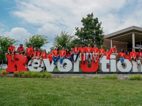 group of students sit on Revolutionary monument at Rutgers Visitor Center